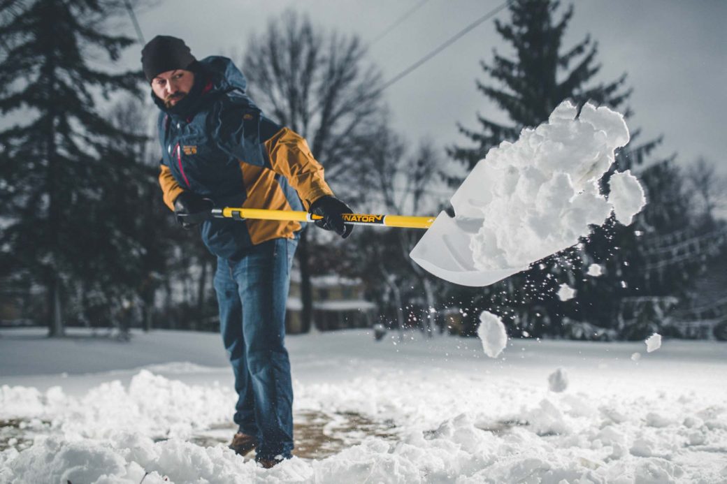 Man throwing snow with shovel.